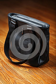 Black notebook peeking out of the pocket of a black leather bag close-up, macro Handmade, natural materials