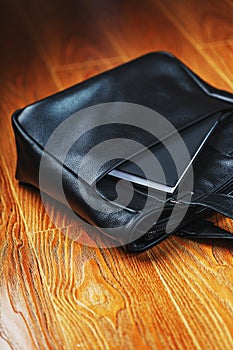 Black notebook peeking out of the pocket of a black leather bag close-up, macro Handmade, natural materials