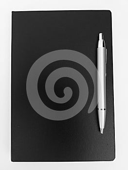 Black notebook and a silver pen