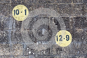 Black numbers in a yellow circle painted on dark brickwork wall in the outdoors