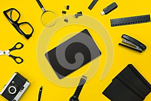Black objects from the office on a yellow background. Work and creativity. Top view.