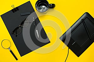 Black objects from the office on a yellow background. Work and creativity. Top view.