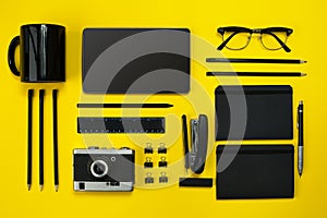 Black objects from the office on a yellow background. Work and creativity. Top view.