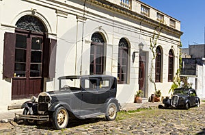 Black and obsolete cars on one of the cobblestone streets, in the city of Colonia del Sacramento, Uruguay. It is one of the oldest