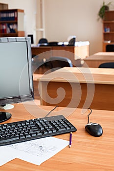 Black off computer monitor with keyboard and mouse on office desk, empty room