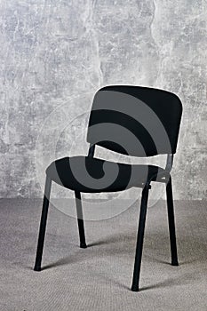 Black office chair in empty room with gray texture wall background