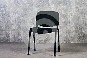 Black office chair in empty room with gray texture wall background