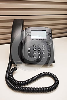 Black office IP Phone on office cubicle desk