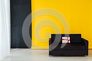 Office sofa with red gifts in the interior of the room with a yellow background