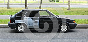 A black old car is parked near the lawn