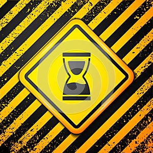 Black Old hourglass with flowing sand icon isolated on yellow background. Sand clock sign. Business and time management