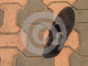 Black old and wornout shoe on brick floor photo