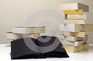 Black open book in foreground of two piles of books
