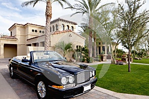 Black open roof car parked outside mansion house photo