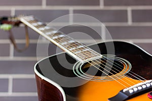 Black and orange acoustic guitar over brick wall background