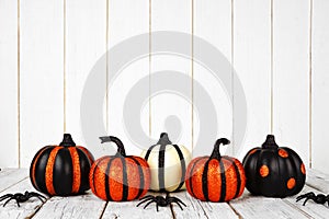 Black and orange glittery Halloween pumpkins against white wood