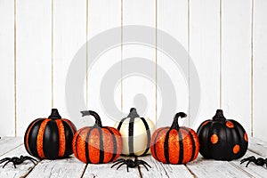 Black and orange glittery Halloween pumpkins against white wood photo