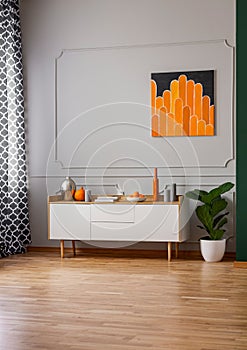 Black and orange painting on empty grey wall of stylish room