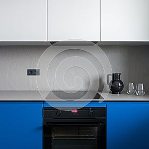 Black oven and induction hob in minimalist kitchen, close-up