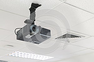 A black overhead projector on ceiling indoors.