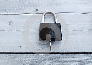 Black padlock on a white wooden background. The concept of security.