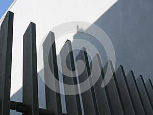 Black painted metal fence in front of a white wall