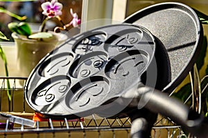 Black pancake smile frying pan on plate drainer rack in kitchen