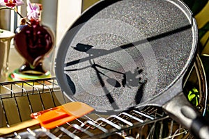 Black pancake smile frying pan on plate drainer rack in kitchen