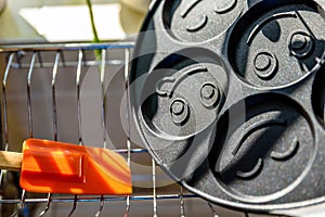 Black pancake smile frying pan on plate drainer rack in kitchen