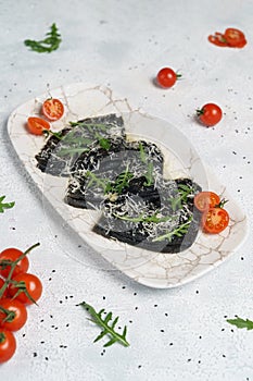 Black pancakes stuffed with red salmon caviar