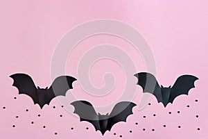 Black paper bats flying over pink colored background. Halloween and decoration concept