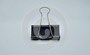 Black paper clip isolated on gray white background. Black metal paper clip.