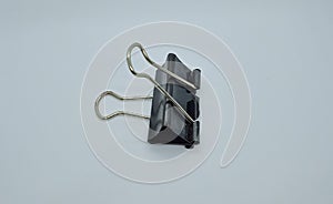 Black paper clip isolated on gray white background. Black metal paper clip.