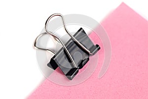 Black Paper clip and pink paper on white background