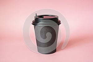 Black paper coffee mug on a pinkbackground. Empty space for text and design. The form for the name of the coffee or company or