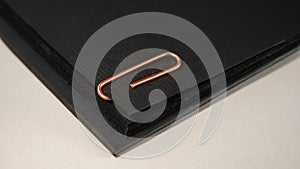 Black paper connected with a golden paper clip on a light background