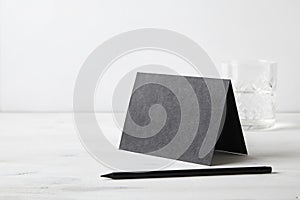 Black paper postcard and pencil on wooden table. Stationery. Blank space for design layout