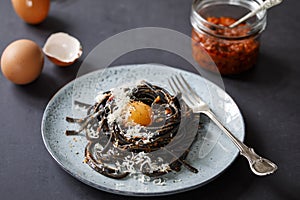 Black pasta with red pesto and egg yolk