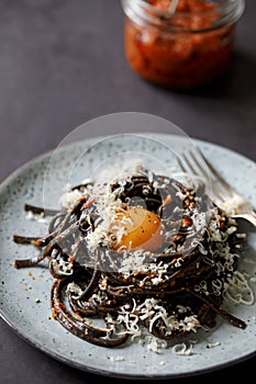 Black pasta with red pesto and egg yolk