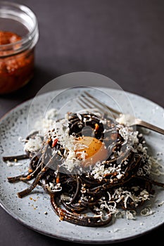 Black pasta with red pesto and egg yolk