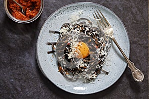 Black pasta with red pesto and egg yolk