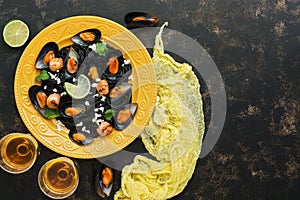 Black pasta spaghetti with mussels, scallops and white wine on a rustic background. Mediterranean food. Top view, copy space