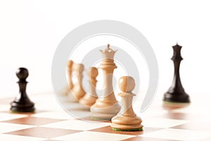 black pawn on a chessboard with white chess pieces