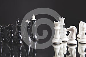 Black pawn among white chess on black background