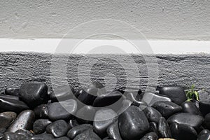 Black pebble stones or rocks with white wall for texture and background Shining smooth natural
