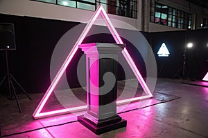 Black pedestal with neon pink light in triangular frame