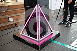 Black pedestal with neon pink light in triangular frame