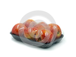 Black peel with six apples wrapped in transparent plastic isolated on white background