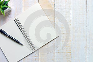 Black pen place on notebook place on white wooden