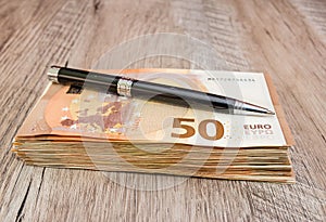 Black pen on a stack with euro banknotes